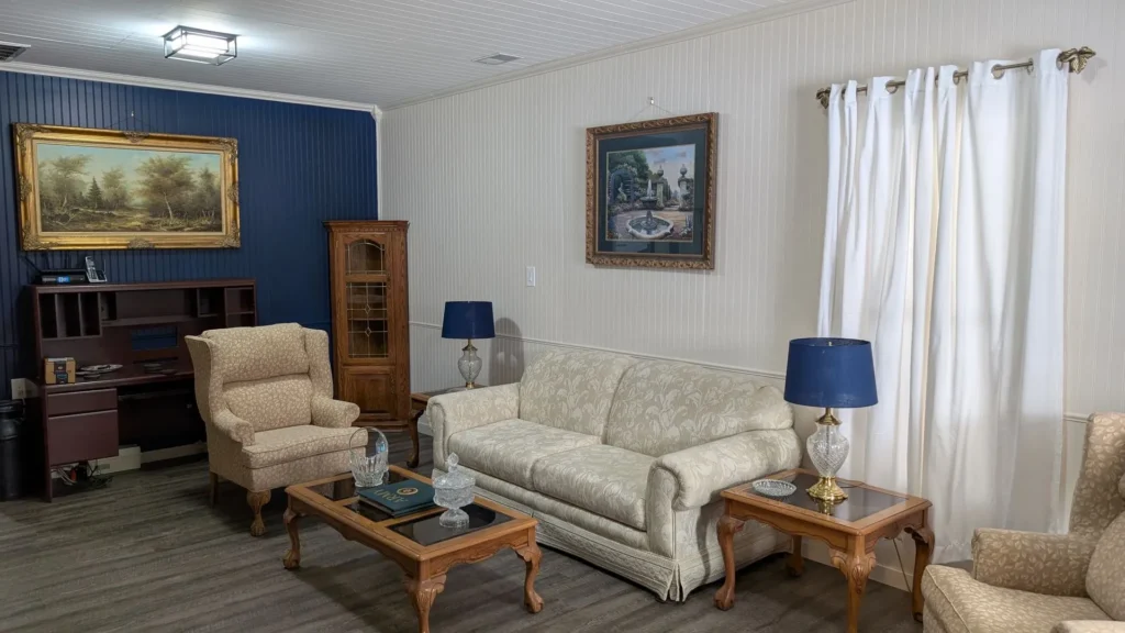 Elegant living room with vintage furniture, blue accents, and framed wall art, creating a cozy, classic ambiance.